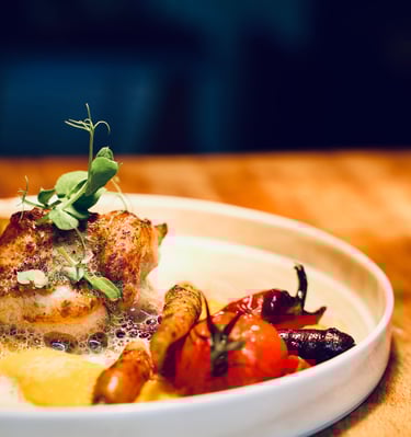 Gros plan d'une assiette blanche avec dedans un plat de poisson et des légumes entiers grillés