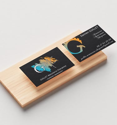 Cartes de visite de l'entreprise GMC posées sur un morceau de bois qui montre le recto et le verso