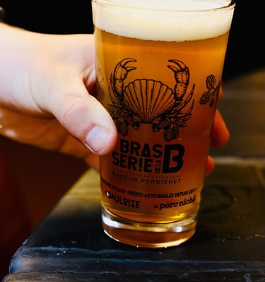 main en gros plan qui pose un verre de bière sur le bord d'une table en bois noir