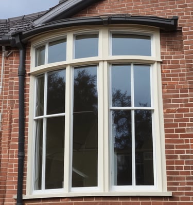 A worker is suspended on ropes, cleaning the windows of a large brick building. The person is equipped with cleaning gear, including a brush and a safety harness attached to a bucket of supplies. The window panes have visible streaks being cleaned, contrasted against the industrial background of brick and metal.