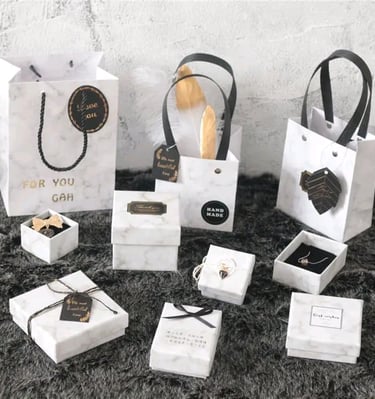Elegant marble pattern gift boxes and shopping bags with black ribbons for luxury jewelry packaging.