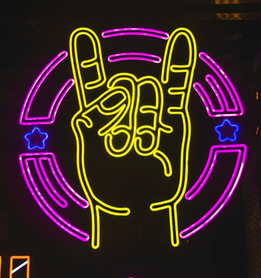 Yellow neon rock on hand gesture sign with pink circular border and blue stars.