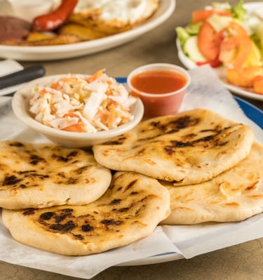 a plate of pupusas with a bowl of cultido and a bowl of salad