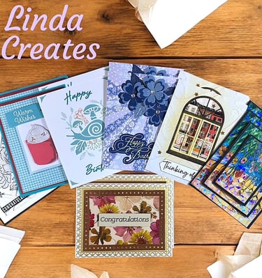 An array of handmade cards laying on a wooden desk.