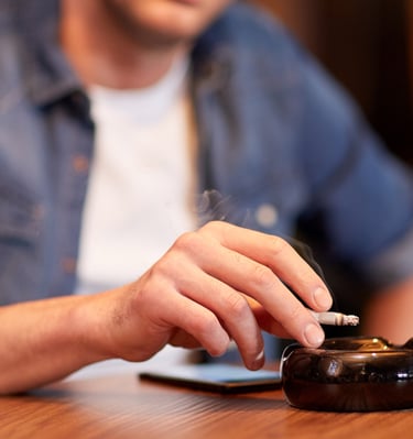 a man sitting at a table with a cigarette in his hand