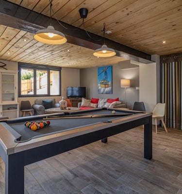 Salle commune du gîte l’Escale 1695 avec billard, coin salon et déco bois pour des vacances détente 