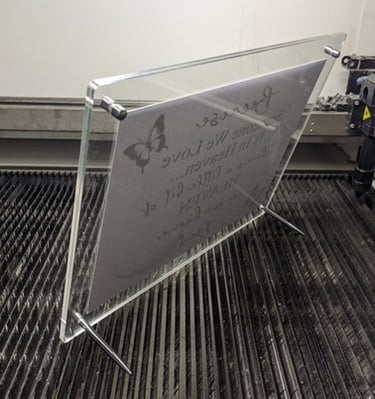 Acrylic standee frame displaying engraved text on a metal surface