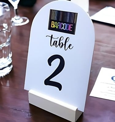 White acrylic table number 2 with a wooden base on a table.