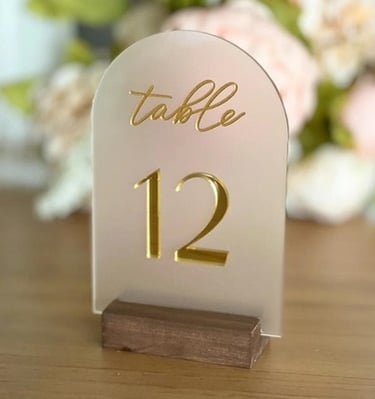 Clear acrylic table number 12 with gold text and a wooden base.