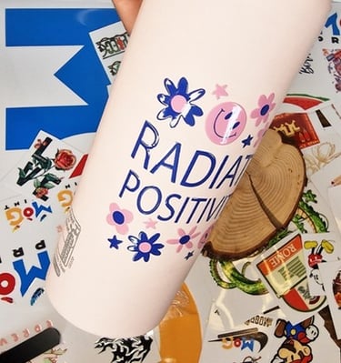 "Radiate Positivity UV DTF transfer sticker applied to a white bottle.