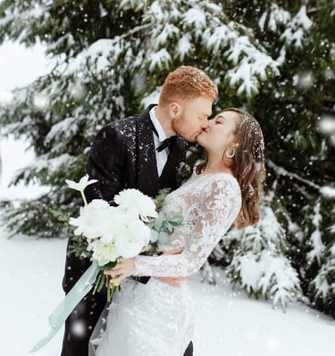 a bride and groom kissing in the snow