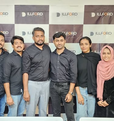 a group of men and women standing in front of a wall with a large banner - Illford Digital Academy