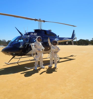 two astronauts standing in front of a helicopter