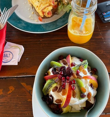 a bowl of fruit salad with a glass of orange juice