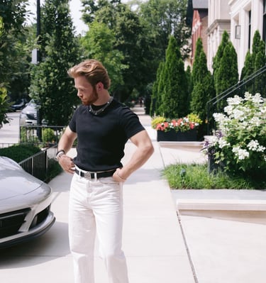a man standing on a sidewalk with a car parked in front of him