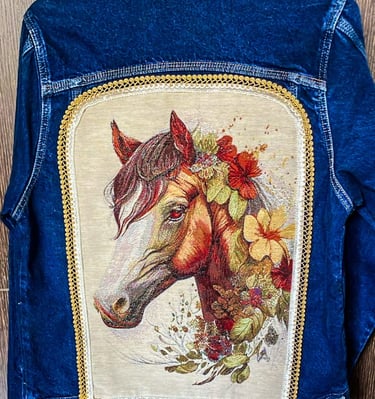 Topacio-pintura textil y apliques de tela y randas sobre espalda de chaqueta de jean azul- Cabeza de caballo y flores