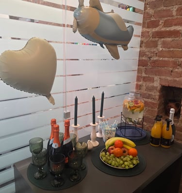 Party drinks and fruit platter with champagne and balloons on a table.