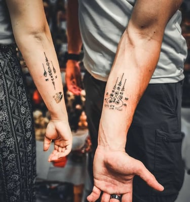 a couple holding hands with matching traditional thai tattoos sak yant on their arms