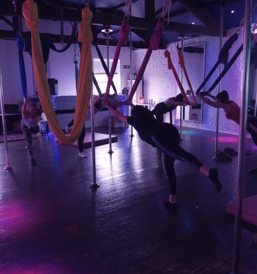 Image of Sxefit aerial silks class in a strength and balance exercise pose