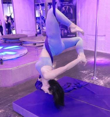 Image of student at Sxefit aerial silks class suspended above a crash mat