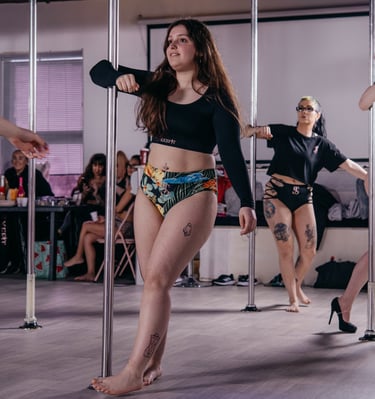 Image of student posing by the pole in a Sxefit pole dancing class