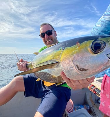 A man holding a fish in his hands during a Zanzibar fishing charter, perfect for Zanzibar fishing