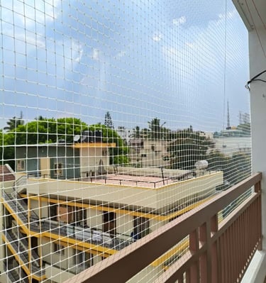 Evening shot of a balcony with pigeon netting, city lights glowing softly in the background.