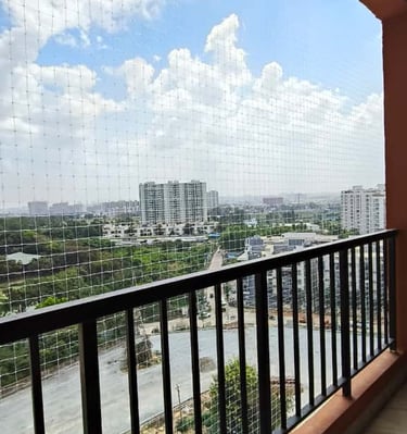 Close-up of a securely installed safety net on a balcony with a curious cat peeking through
