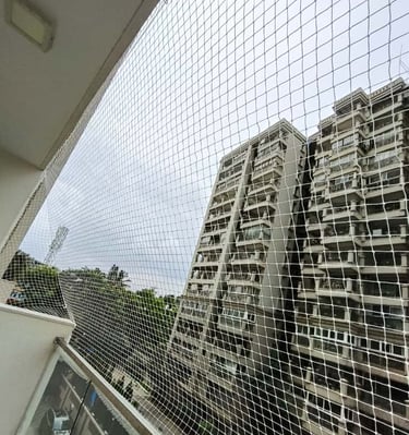 A happy dog safely playing behind a window protected by Arjilli safety nets