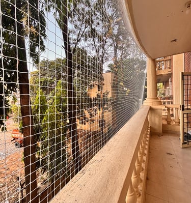 Close-up of a sturdy white pigeon net securely fitted on a balcony railing in Whitefield.