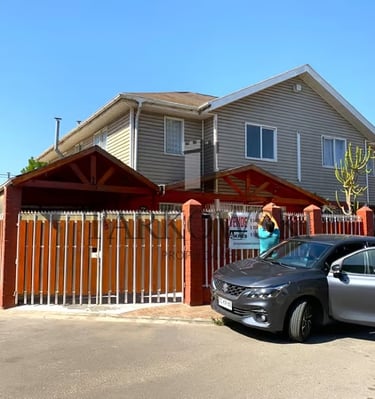 casa gris dos pisos con portón de madera y estacionamiento tipo quincho 