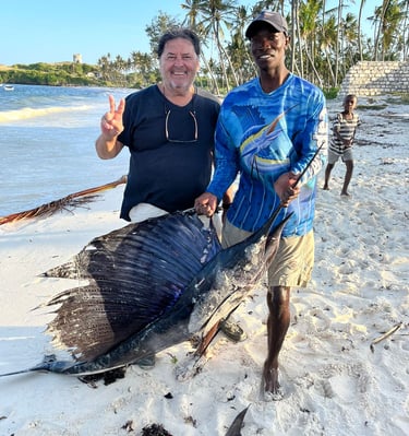 a man holding a fish on a beach