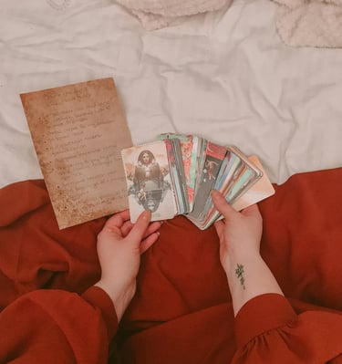 Hands holding tarot cards with a handwritten manifestation list — personal reading by Amber, Queen of Wands.