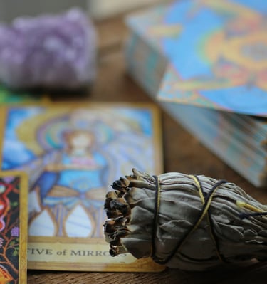 Sage bundle, amethyst crystal, and colorful tarot deck used in Amber’s energy readings.