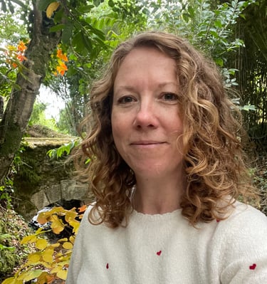 Headshot of Iona Reading standing in front of trees and a bridge