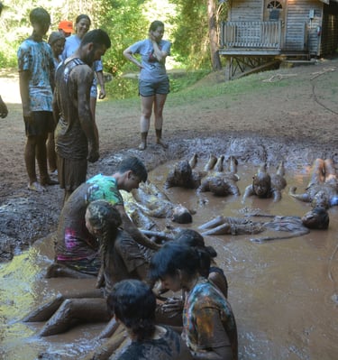 a group of people standing around a muddy puddle