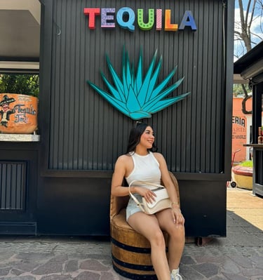 a woman sitting on a barrel chair in front of a tequila bottle