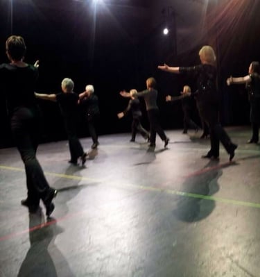 a group of adults tap dancing in a recital in a dance pose