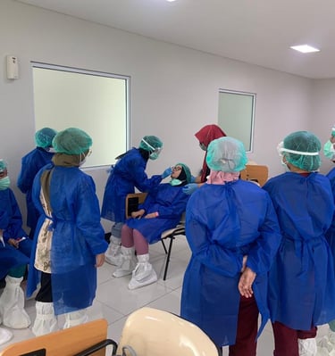 Tim medis mengenakan APD biru sedang bersiap dan berdiskusi di ruang isolasi rumah sakit