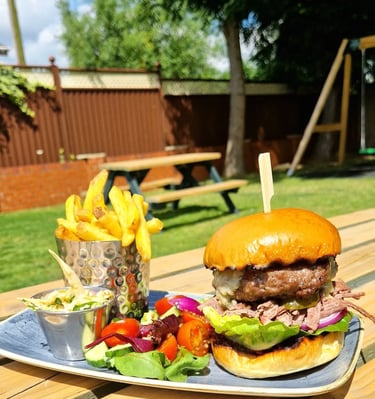 a hamburger and fries with salad in a beer garden
