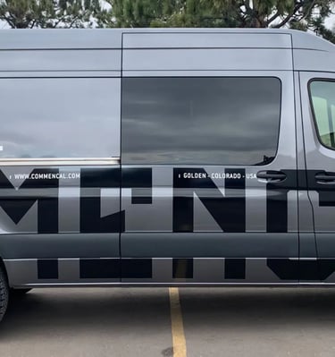 a van with a commercial vehicle WRAP parked in front of a building