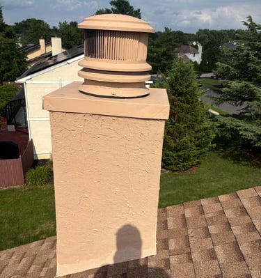 A newly waterproofed and resurfaced chimney with a modern round chimney cap, installed by Roslyn Chimney in Roslyn, New York