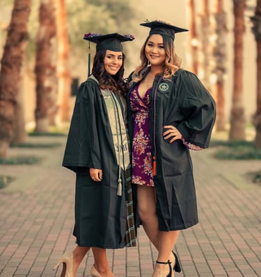 two women in graduation gowns posing for a photo