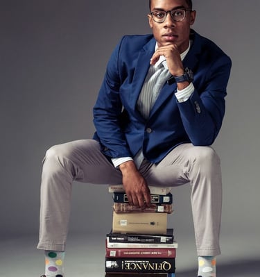 a man in a suit and tie is sitting on a stack of books