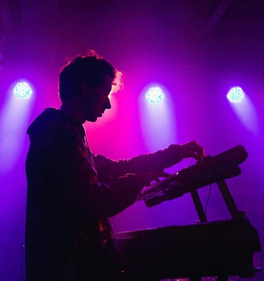 um homem tocando teclado em um quarto escuro