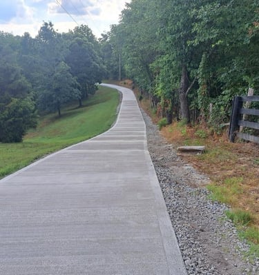 a paved road with a wooden fence and a bench