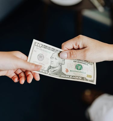 two people holding onto a dollar bill representing gold ira fees and a guide to understanding gold ira fees