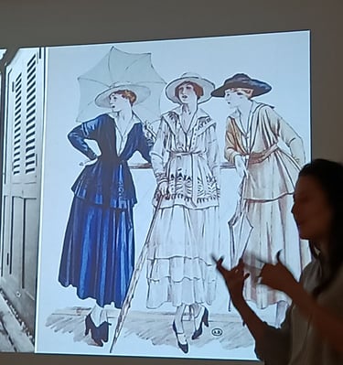 Une conférencière présente une illustration de la mode féminine et des robes d’époque vintage.