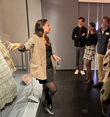 Une guide montre des robes victoriennes à un groupe de visiteurs au musée de la mode de Paris.