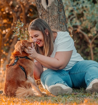 ragazza che sorride al proprio cucciolo seduta sotto un albero